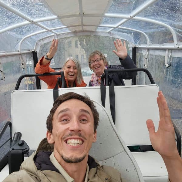 Smiling tourists on a rainy day enjoying a private tuk tuk tour in Sintra with Daniel Ponce from Yes, You Deserve! – covered electric tuk tuk ensuring comfort in all weather conditions.