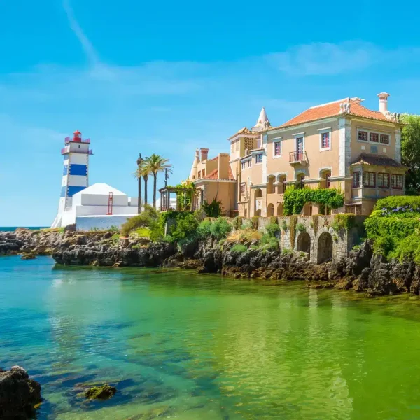 Scenic view of Santa Marta Lighthouse and museum in Cascais, Portugal, with turquoise waters, palm trees, and traditional Portuguese architecture – perfect stop on a Cascais day tour.