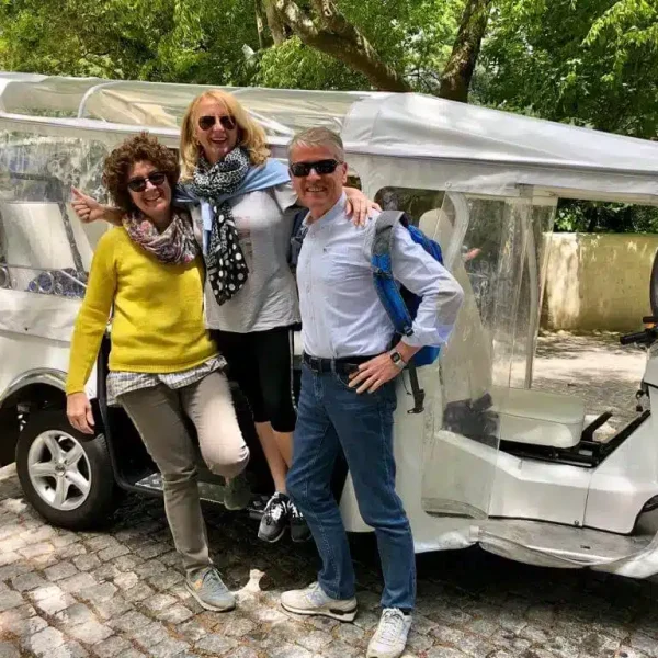Happy tourists posing next to an electric tuk tuk in Sintra, Portugal during a private guided tour with Yes, You Deserve – a fun and comfortable way to explore the region’s top landmarks with a local expert.